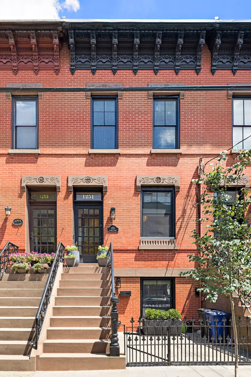 Brick rowhouse facade, decorative cornice and front stoop at 1251 Garden Street in Hoboken