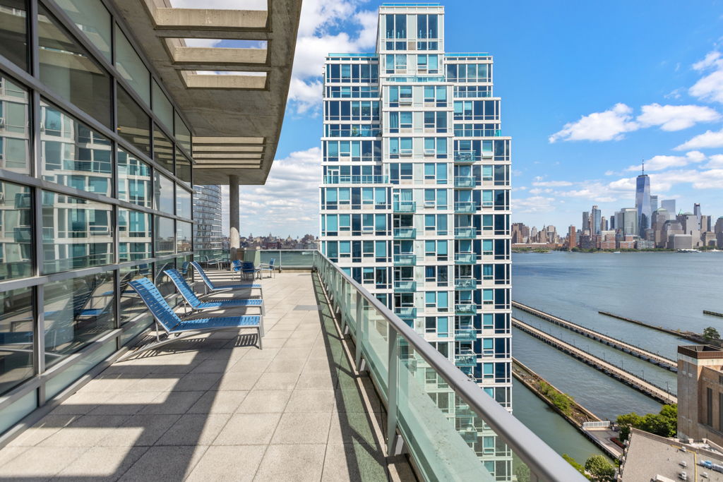 Outdoor terrace with lounge chairs and Hudson River views at the Shore Club in Newport, Jersey City